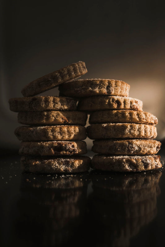 Stack of chocolate chip Welsh Cakes on a dark surface with a blurred background. 
